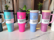 Set of colorful vacuum insulated tumblers on a marble surface with plants in the background.