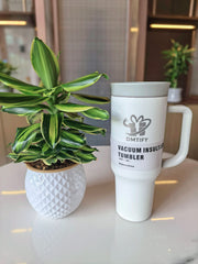 White vacuum insulated tumbler with a plant on a table