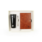 Set of black travel mug, brown notebook, and pen in a box on a white background