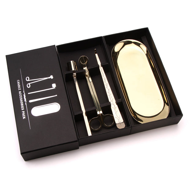 Gold candle accessories set in a black box on a white background