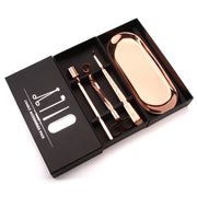 Rose gold candle care tools in a black box on a white background
