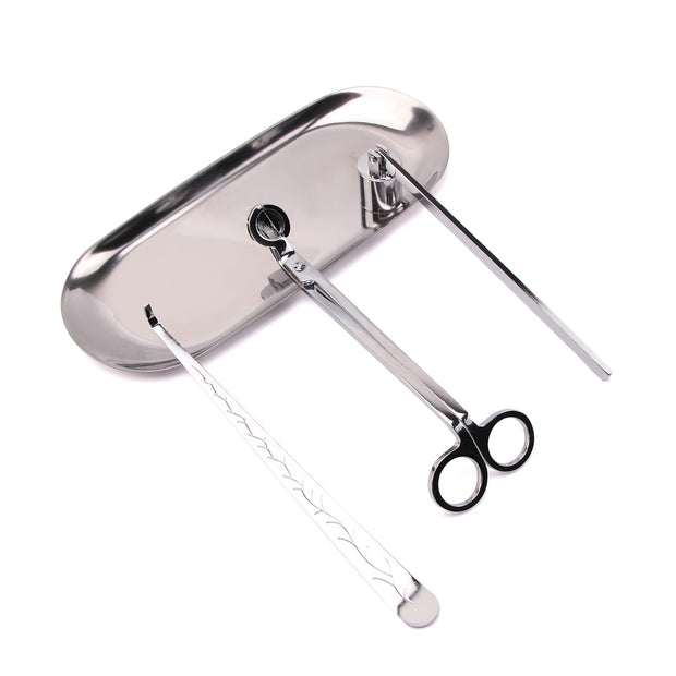 Set of silver candle accessories including wick trimmer, dipper, snuffer and tray on a white surface.