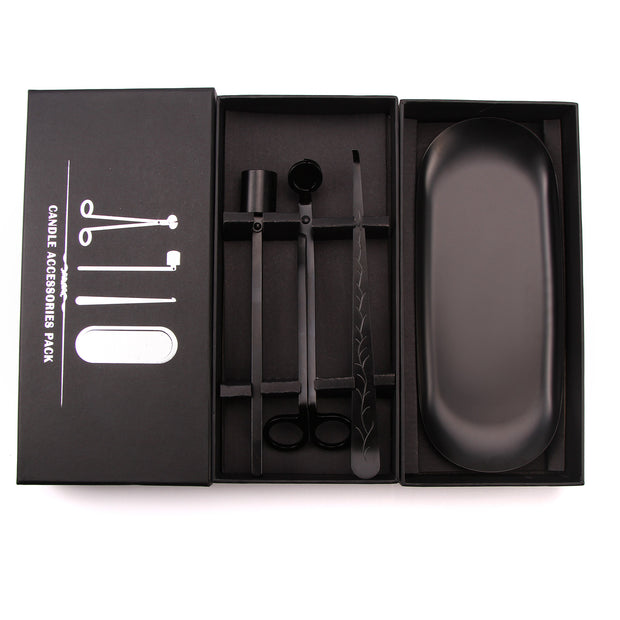 Black candle accessories set in an open box on a white background