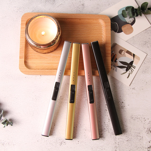 Four cylindrical candles lighter  in different colours on a wooden tray with a lit candle.